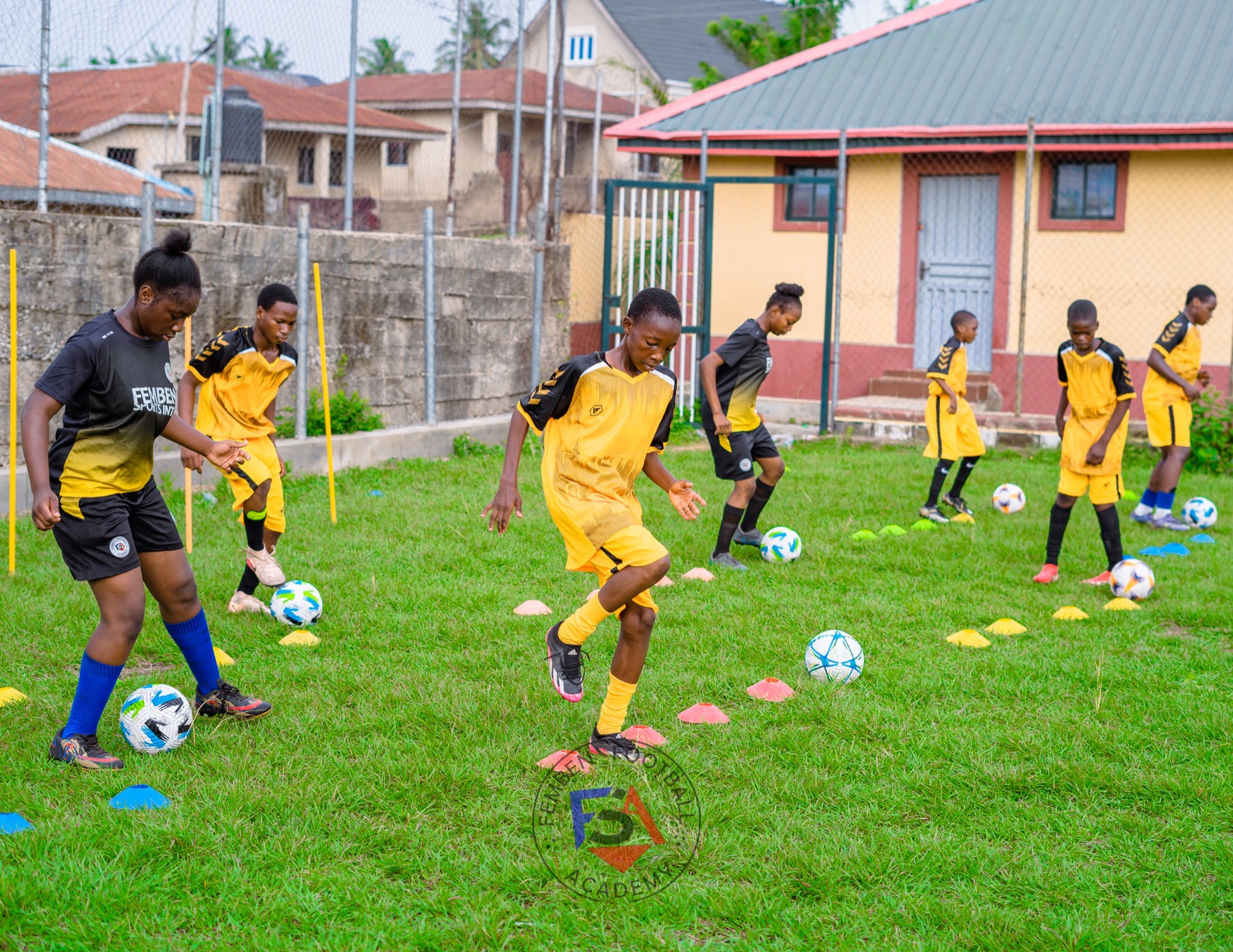 Young players practising football dribbling drills between training cones.